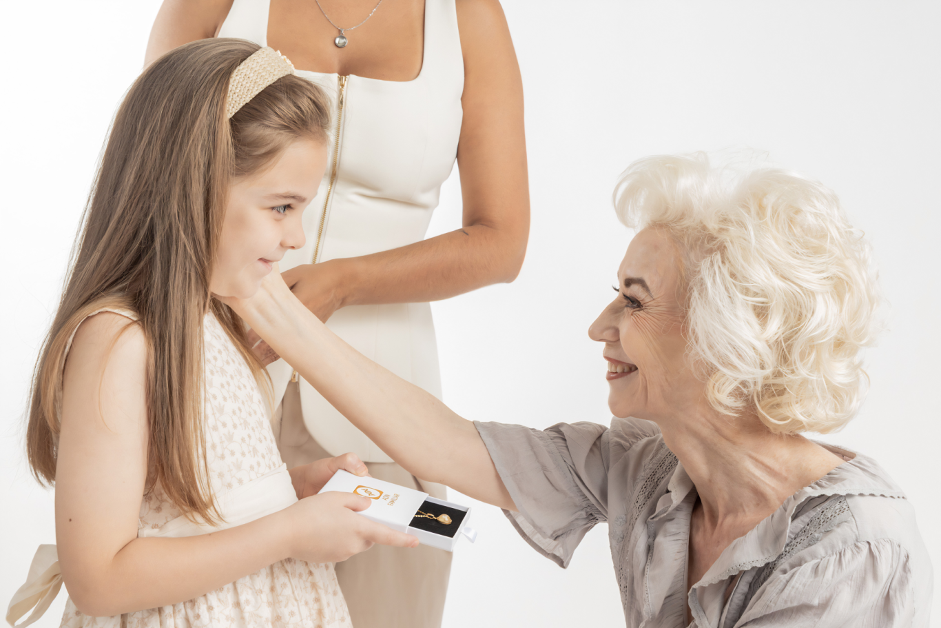 El mejor regalo para ella Niña recibiendo un regalo de una mujer mayor, con otra mujer en el fondo.